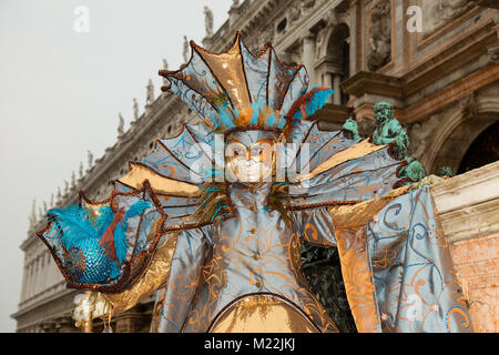 Il Carnevale di Venezia - Femmina maschera veneziana in un colorato ed elegante costume su Piazza San Marco a Venezia con la tradizionale architettura veneziana Foto Stock