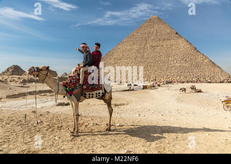 Due ragazzi egiziani su un cammello di fronte alla grande Piramide di Khufu (Cheope) a Giza Foto Stock