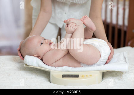 La mamma è la misurazione di baby pesare su scale a casa Foto Stock