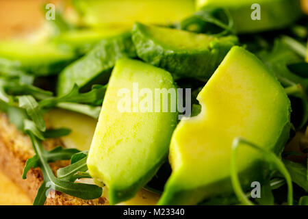 Bruschetta vegetariana con avocado e rucolla od un tavolo di legno. Foto Stock