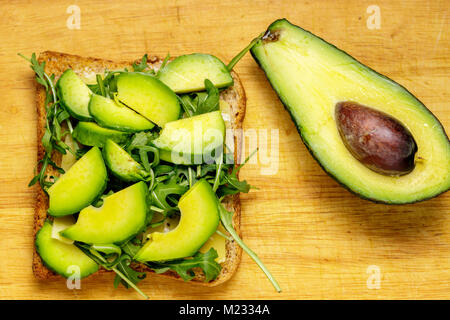 Bruschetta vegetariana con avocado e rucolla od un tavolo di legno. Foto Stock