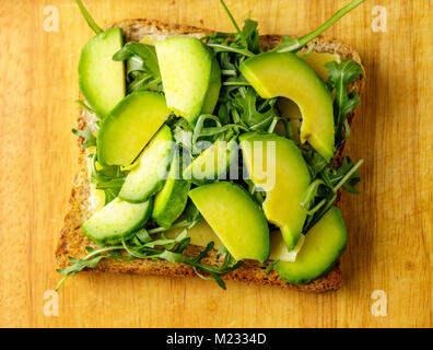 Bruschetta vegetariana con avocado e rucolla od un tavolo di legno. Foto Stock