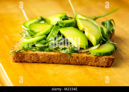Bruschetta vegetariana con avocado e rucolla od un tavolo di legno. Foto Stock