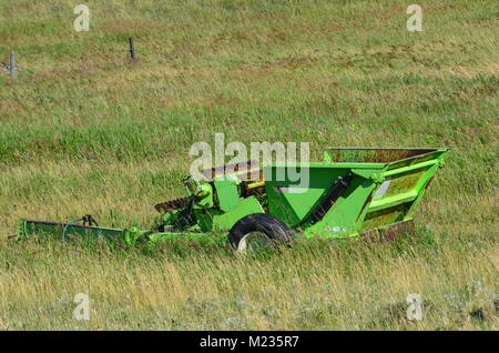 Vecchia fattoria abbandonata attrezzature si siede in un campo di agricoltori arrugginimento lontano Foto Stock