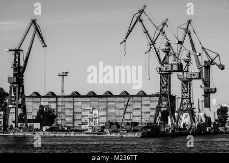 Cantiere di Danzica, Polonia. In stile retrò in bianco e nero. Gru, il cantiere di vecchi edifici, strutture arrugginite. Foto Stock