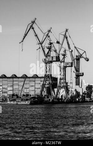 Cantiere di Danzica, Polonia. In stile retrò in bianco e nero. Gru, il cantiere di vecchi edifici, strutture arrugginite. Foto Stock