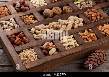 Vari dadi selezione: arachidi, nocciole, castagne, noci, pistacchi e le noci pecan in una scatola di legno Foto Stock