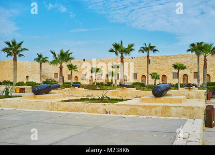 La cittadella Qaitbay è decorata con Palm Garden e vecchi cannoni, in piedi lungo il vicolo centrale ad Alessandria, Egitto. Foto Stock