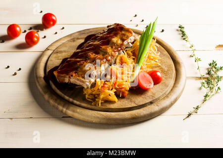 Nervature arrosto spruzzata con salsa con stufati di cavolo nero su un giro di tavola di legno Foto Stock