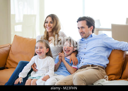 Adorabili e famiglia con due bambini di guardare la tv in soggiorno e sorridente Foto Stock