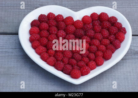 Cuore rosso fatta di lampone. Fresche, succosa e fragrante di frutti di bosco Lamponi sono posati su un piatto. Foto Stock