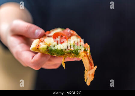 Mano trattiene fetta tagliata vicino pizza Foto Stock