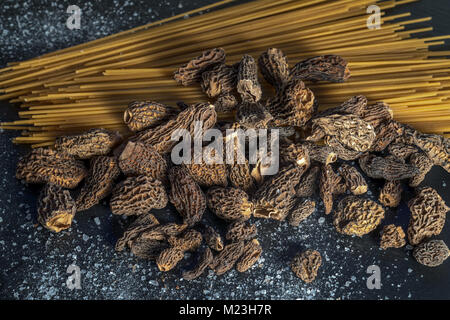 Morilles e spaghetti sulla tavola nera Foto Stock