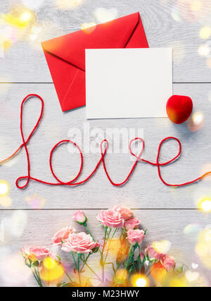 Busta rossa con la lettera e rose fiori su sfondo di legno. Il giorno di San Valentino sfondo Foto Stock