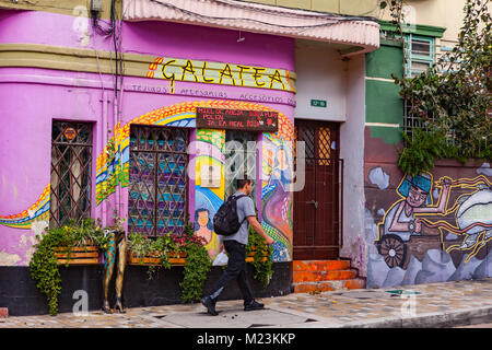 Bogotà, Colombia - 28 Maggio 2017: un colombiano locale uomo cammina passato qualche dipinto luminosamente facciate in Candelaria nel quartiere della capitale Foto Stock