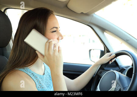 Vista laterale verticale di un conducente distratto chiamando al telefono con la guida di una vettura Foto Stock