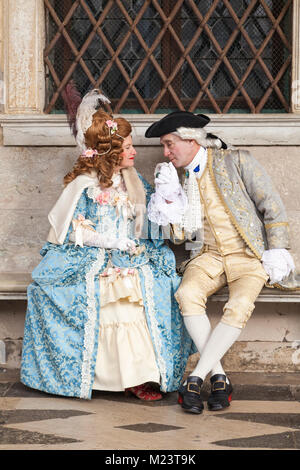 Il Carnevale di Venezia 2018, Venezia, Italia. Coppia romantica in costume classico seduto presso il Palazzo dei Dogi con l'uomo di baciare la mano di donna Foto Stock