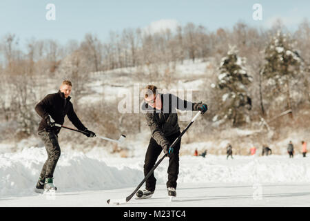 Due uomini giocare hockey su ghiaccio su un lago ghiacciato Foto Stock