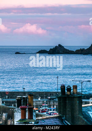 Gardenstown, Aberdeenshire, Scotland, Regno Unito. Bellissime le Nuvole rosa al tramonto colori guardando ad est del porto, tetti e comignoli Foto Stock