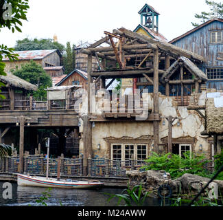 Vecchio trading post sul fiume con travi di legno esposte. Torre campanaria e vuoto barca ancorata. Lost River Delta attrazione a Tokyo Disney Sea. Foto Stock