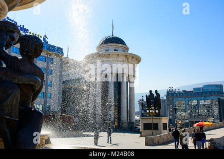 SKOPJE, MACEDONIA - 12 ottobre 2017: Macedonia Square nella città di Skopje con il museo archeologico e i monumenti shot attraverso fontana Foto Stock