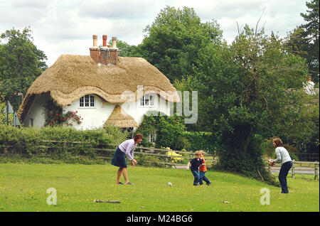 Famiglia giocando nella parte anteriore di Nuova Foresta cottages Foto Stock