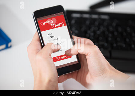 Close-up di una persona di navigazione Online Dating Website su Smart Phone Foto Stock