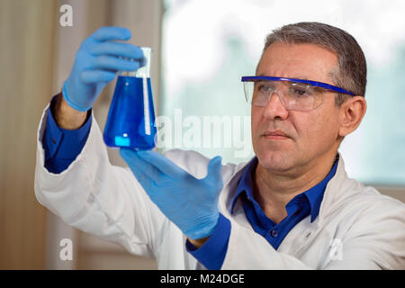 Scienziato indossando indumenti di protezione, lavorando in laboratorio. Foto Stock