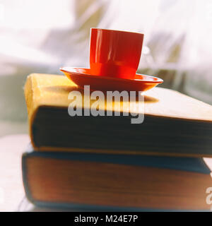 Tazza di caffè su libri vecchi. Finestra della camera. Foto Stock