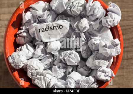 Carta sgualcita racismo scritta, portoghese e la parola spagnola per il razzismo, all'interno del cestino. Palline di carta. Vecchio e abbandonato idea o pratica. Macro p Foto Stock