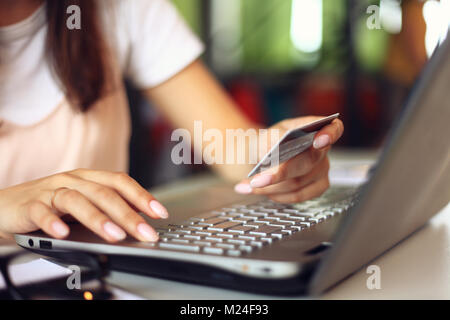 Giovane donna tenendo la carta di credito e con il computer portatile. Shopping online concetto. Foto Stock