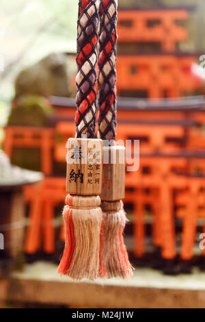 Corda di un Suzu, Giapponese sacrario scintoista campana con offrendo scritto su di esso a Fushimi Inari shrine in Kyoto, Giappone. Foto Stock