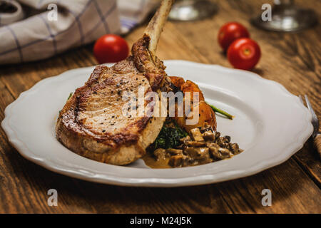 Cotto al forno costolette di maiale o cotoletta con salsa di funghi e patate con spinaci Foto Stock