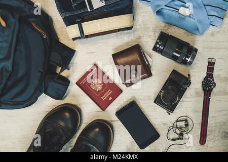 Una serie di accessori per viaggiare su una tavola di legno bianco sfondo vintage. flat laici. Avventura e wanderlust Concetto di immagine con accessori da viaggio. Preparata Foto Stock