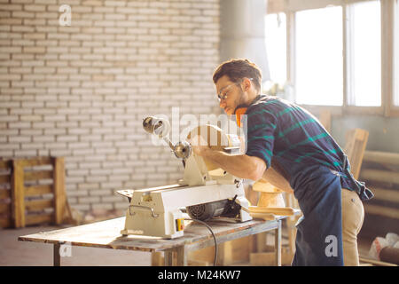 Attraente uomo iniziare facendo lavori in legno in falegnameria Foto Stock