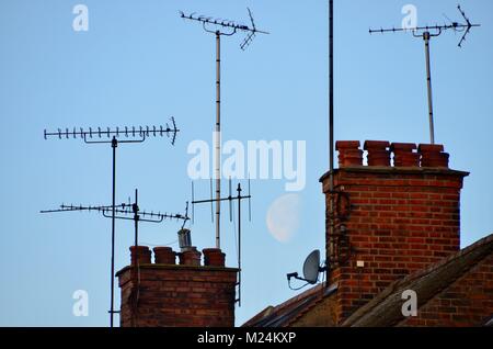 Antenne e comignoli su Londra case con una grande luna dietro Foto Stock