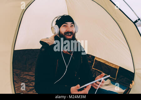 Uomo Barbuto con la compressa a ridere Foto Stock