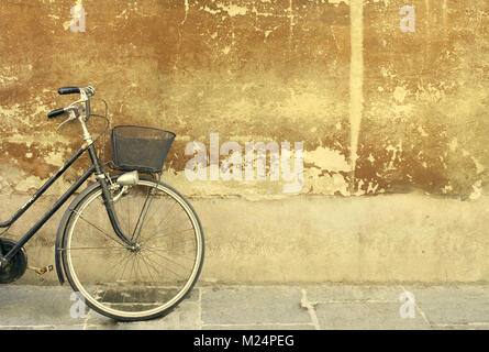 Particolare di una parte di una bicicletta appoggiata contro un vecchio muro Foto Stock