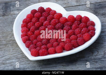 Cuore rosso fatta di lampone. Fresche, succosa e fragrante di frutti di bosco Lamponi sono posati su un piatto. Foto Stock