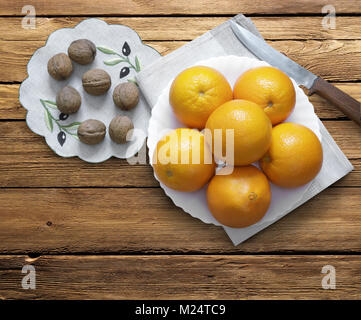 Sfondo bianco piatto con arance, un coltello e noci. La vista dall'alto. Foto Stock