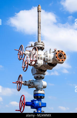 Olio bene dopo la riparazione nel fango e pozzanghere. Olio e apparecchiature di testa del pozzo. La valvola manuale con volantino di manovra di apertura e chiusura della linea di flusso Foto Stock