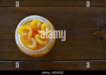 Un vaso aperto di conserve di arance su di un tavolo di legno Foto Stock