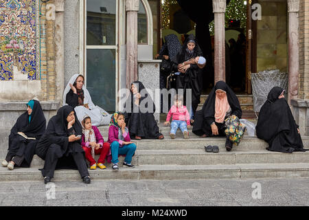 Tehran, Iran - 27 Aprile 2017: le donne iraniane in hijabs e bambini seduti sui gradini vicino lo Shah Abdol Azim Santuario. Foto Stock