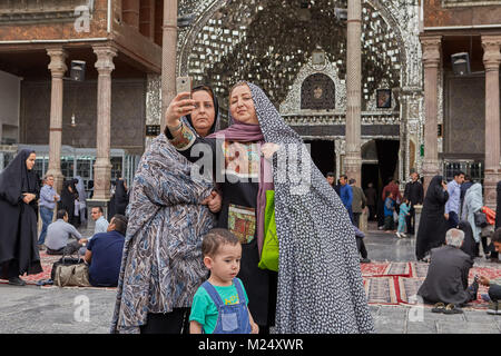 Tehran, Iran - 27 Aprile 2017: le donne iraniane con un bambino di scattare foto sullo sfondo del Shah Abdol Azim Santuario portale opposta con un loft Foto Stock