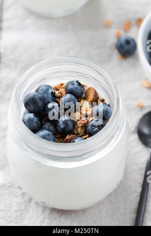 Yogurt con mirtilli freschi e granola in un vaso. Messa a fuoco selettiva. Uno stile di vita sano e perdita di peso concept Foto Stock