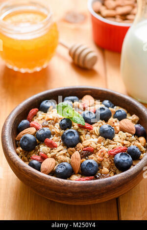 Muesli con frutta secca, noci e mirtilli freschi nella ciotola di legno. Uno stile di vita sano e salutare prima colazione, dieta e perdita di peso concept Foto Stock