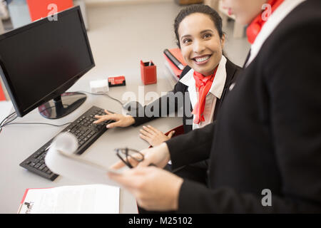 Angolo alto ritratto di due graziose imprenditrici vestita di nero e rosso uniforme di chat a scrivania in ufficio moderno Foto Stock