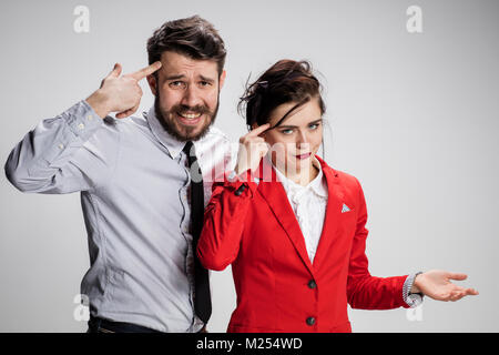 Il triste business l uomo e la donna in conflitto tra loro su uno sfondo grigio Foto Stock