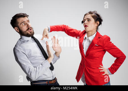 Il triste business l uomo e la donna in conflitto tra loro su uno sfondo grigio Foto Stock