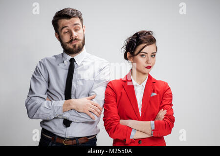 Il triste business l uomo e la donna in conflitto tra loro su uno sfondo grigio Foto Stock